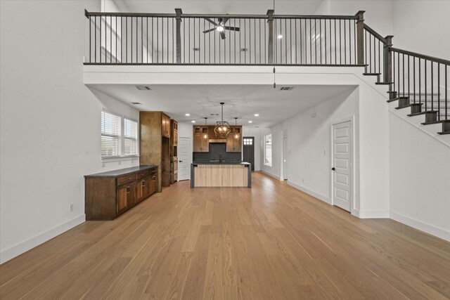 unfurnished living room featuring light wood-style floors, baseboards, and a healthy amount of sunlight