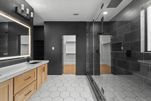 full bath with visible vents, a shower stall, a walk in closet, and tile patterned flooring