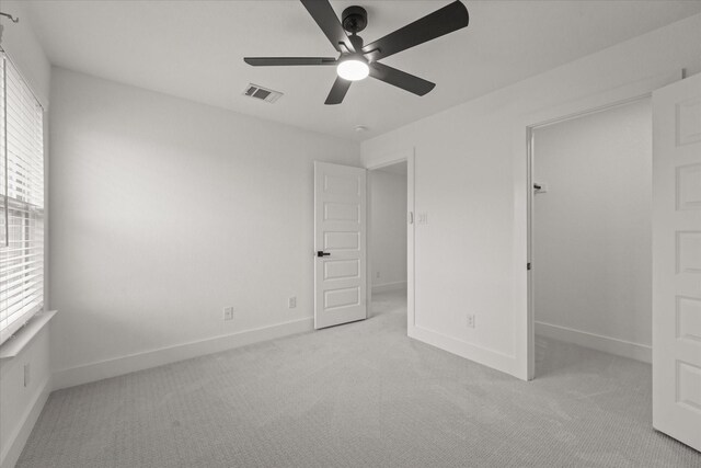 unfurnished bedroom with visible vents, a ceiling fan, baseboards, and light colored carpet