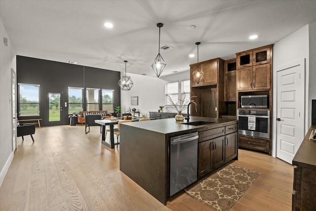 3805 Bluestem Blvd, Denton, TX 76226 - kitchen with stainless steel appliances, light wood finished floors, recessed lighting, decorative light fixtures, and an island with sink