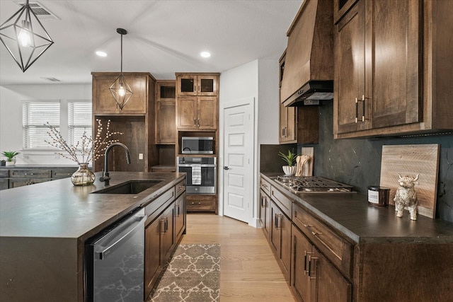 3805 Bluestem Blvd, Denton, TX 76226 - kitchen with appliances with stainless steel finishes, custom exhaust hood, dark countertops, backsplash, and light wood-style floors