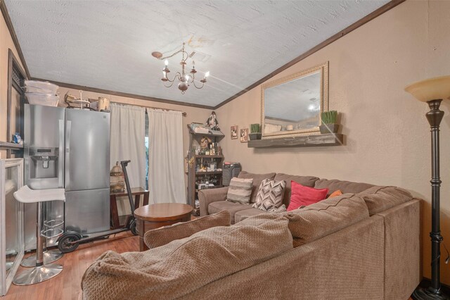 living room with an inviting chandelier, ornamental molding, wood finished floors, and lofted ceiling