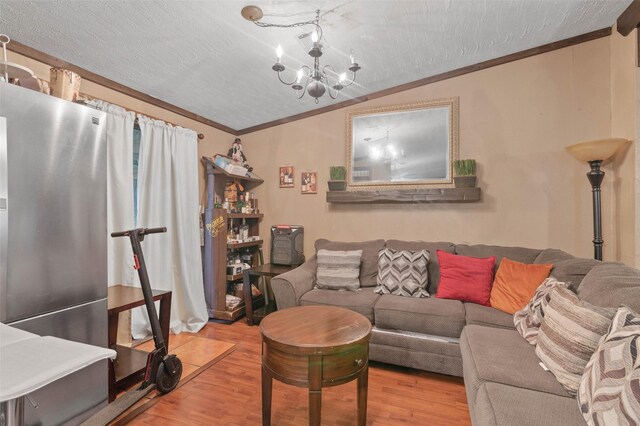 living area featuring an inviting chandelier, crown molding, wood finished floors, and lofted ceiling