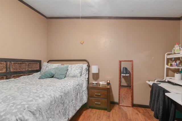 bedroom with crown molding, baseboards, and light wood-style floors