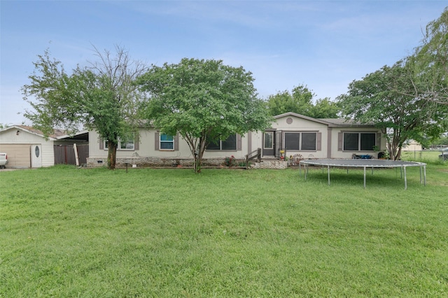 back of property with a lawn, fence, and a trampoline
