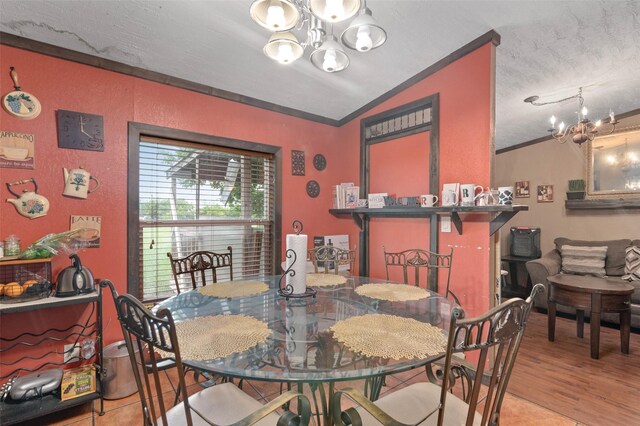 dining room with crown molding, lofted ceiling, a chandelier, and wood finished floors