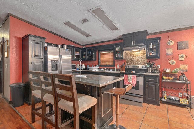 kitchen with visible vents, lofted ceiling, a textured ceiling, under cabinet range hood, and stainless steel appliances