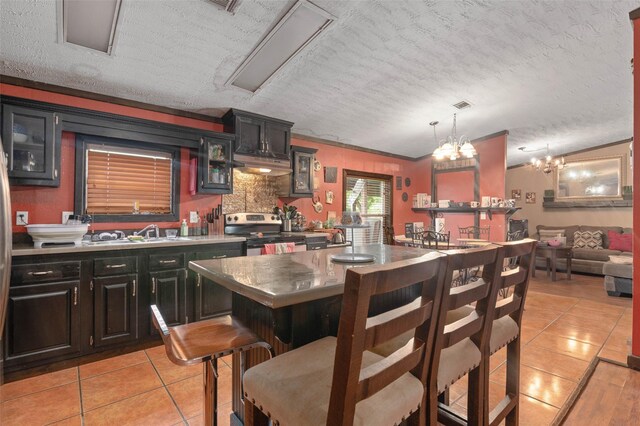 interior space featuring light tile patterned floors, stainless steel electric range oven, a textured ceiling, and glass insert cabinets