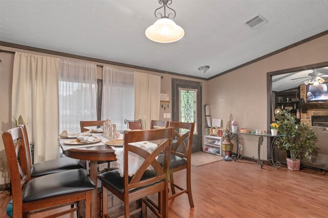 dining area with visible vents, crown molding, lofted ceiling, wood finished floors, and ceiling fan