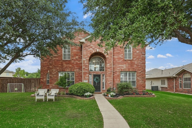 traditional-style house with fence, a front yard, central AC, and brick siding