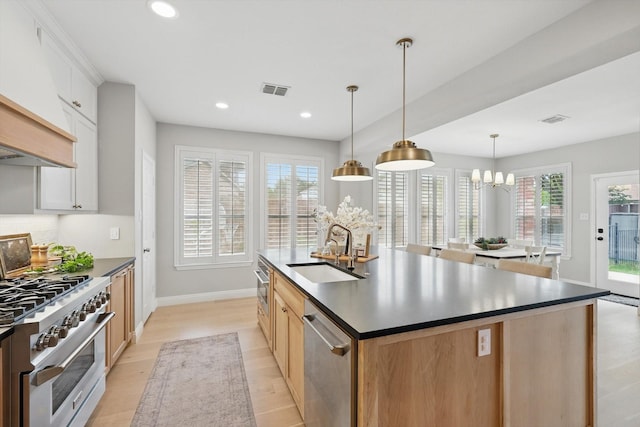 kitchen featuring dark countertops, baseboards, a sink, light wood finished floors, and stainless steel appliances