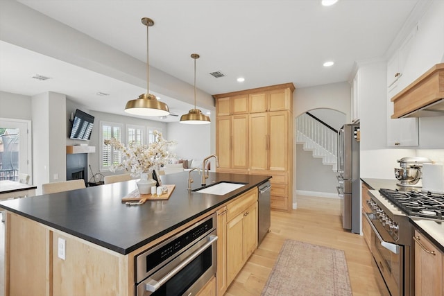 kitchen with visible vents, light brown cabinets, dark countertops, a sink, and stainless steel appliances