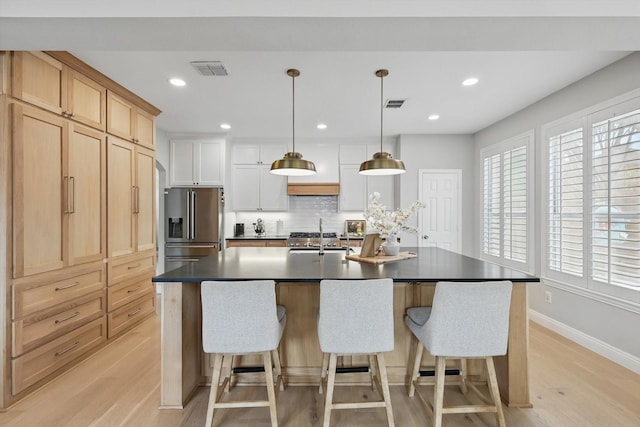 kitchen with light wood-style floors, high quality fridge, a sink, and visible vents