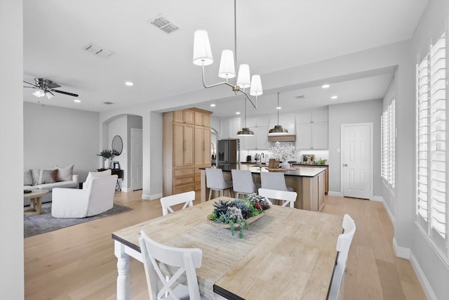 dining room with visible vents, arched walkways, light wood-style flooring, and baseboards