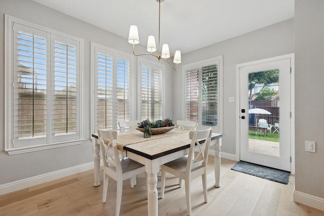 dining area with baseboards, a notable chandelier, and light wood finished floors