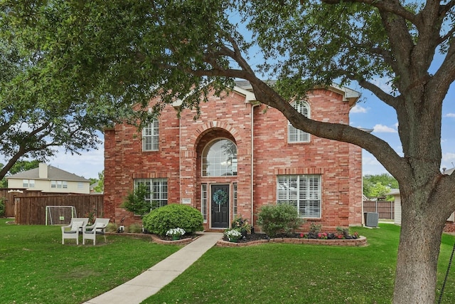 traditional home with fence, a front lawn, and brick siding