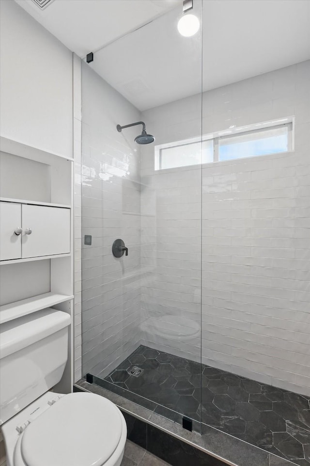 full bathroom with plenty of natural light, a tile shower, and toilet