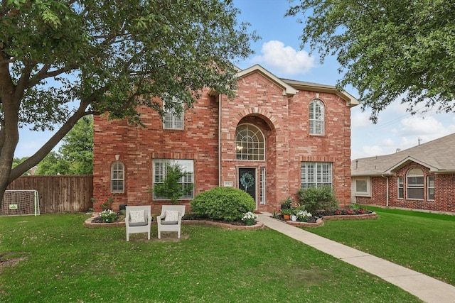 traditional-style house featuring brick siding, fence, and a front yard