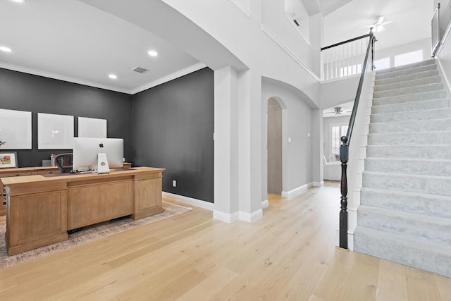 office area with arched walkways, ceiling fan, baseboards, and light wood finished floors