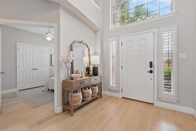 foyer featuring baseboards, ceiling fan, and light wood-style floors