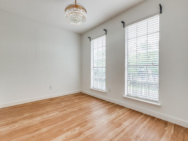 3817 Rawlins St Unit 103, Dallas, TX 75219 - unfurnished room with a chandelier, baseboards, light wood-style floors, and plenty of natural light