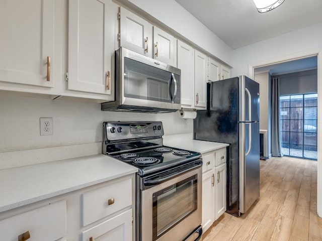3817 Rawlins St Unit 103, Dallas, TX 75219 - kitchen with appliances with stainless steel finishes, light countertops, light wood-style floors, and white cabinetry