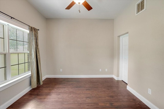 empty room with baseboards, a ceiling fan, dark wood finished floors, and visible vents