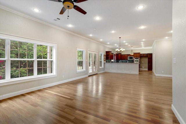 unfurnished living room featuring crown molding, baseboards, ceiling fan with notable chandelier, and light wood-style flooring