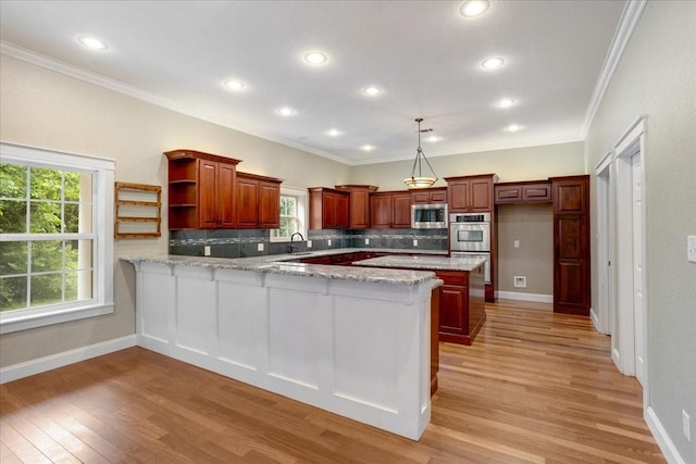 kitchen with a peninsula, light wood-style floors, appliances with stainless steel finishes, and tasteful backsplash