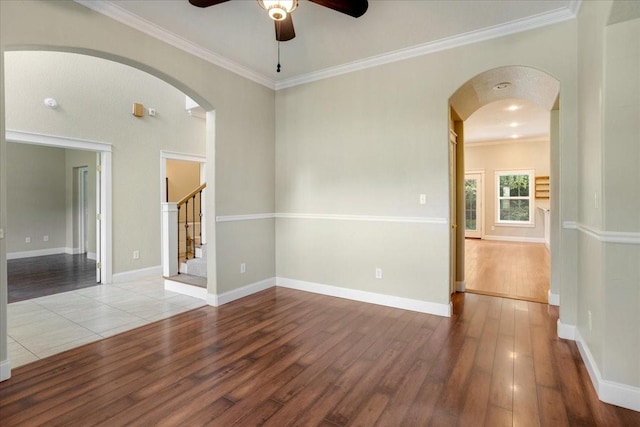 spare room with arched walkways, ornamental molding, a ceiling fan, and hardwood / wood-style flooring