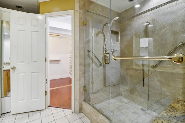 bathroom with a walk in closet, tile patterned flooring, and a stall shower