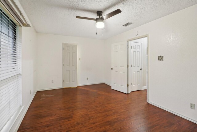 unfurnished bedroom featuring visible vents, baseboards, a textured ceiling, and wood finished floors
