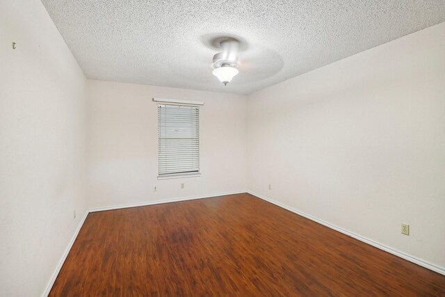 empty room with baseboards, a ceiling fan, a textured ceiling, and dark wood-style floors