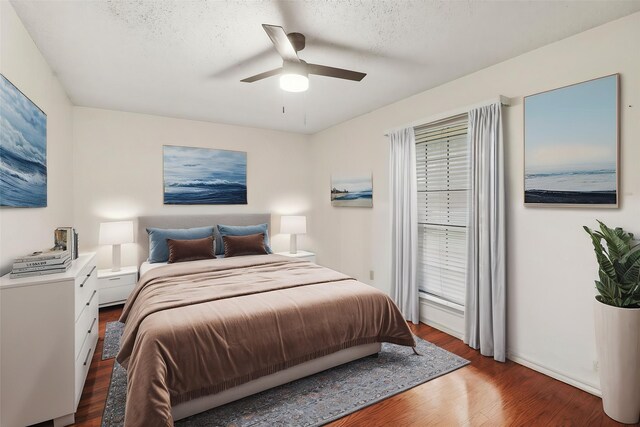bedroom with baseboards, a textured ceiling, ceiling fan, and wood finished floors