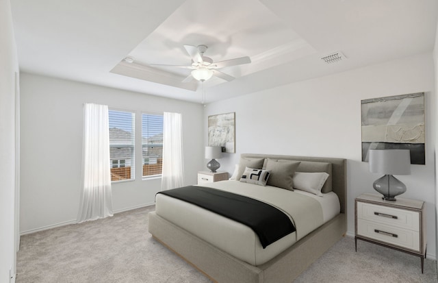 bedroom with light colored carpet, a ceiling fan, baseboards, a tray ceiling, and visible vents