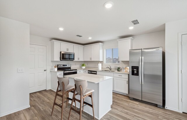 kitchen featuring light countertops, appliances with stainless steel finishes, a kitchen island, and white cabinets