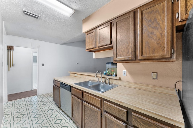 kitchen with a sink, dishwasher, light countertops, a textured ceiling, and visible vents