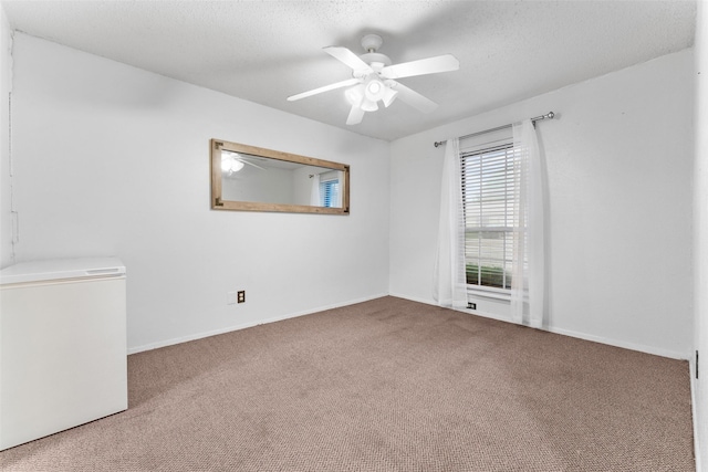 carpeted empty room featuring a ceiling fan and baseboards
