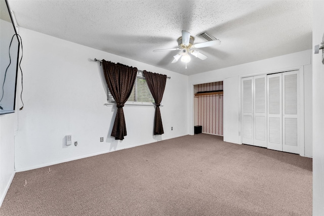 unfurnished bedroom featuring two closets, a textured ceiling, visible vents, and carpet