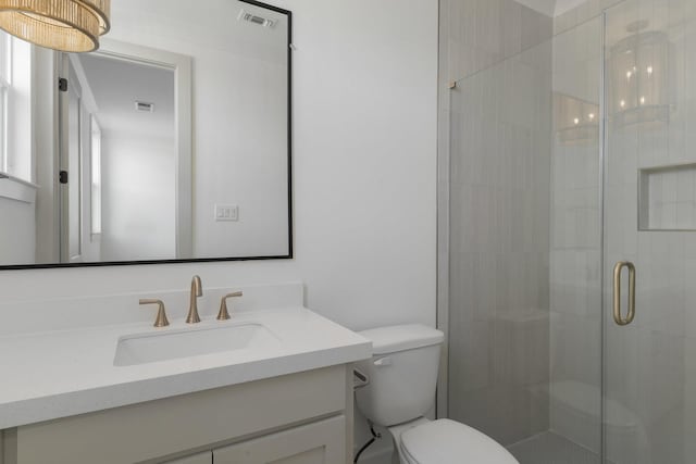 bathroom with vanity, a shower stall, toilet, and visible vents