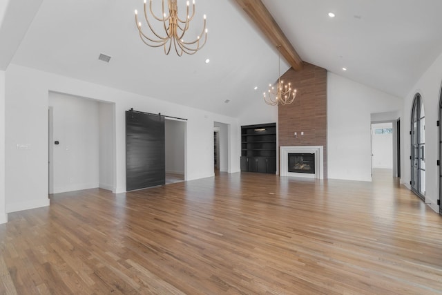 unfurnished living room with a fireplace, beam ceiling, high vaulted ceiling, light wood finished floors, and an inviting chandelier