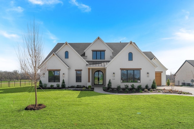 french provincial home featuring a standing seam roof, metal roof, fence, a front lawn, and stucco siding