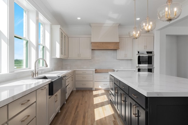 kitchen featuring light stone countertops, an inviting chandelier, a sink, stainless steel appliances, and tasteful backsplash