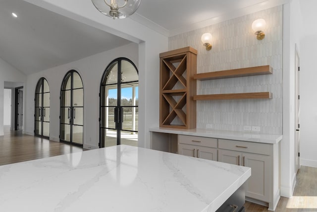 bar featuring baseboards, vaulted ceiling, and light wood-style flooring