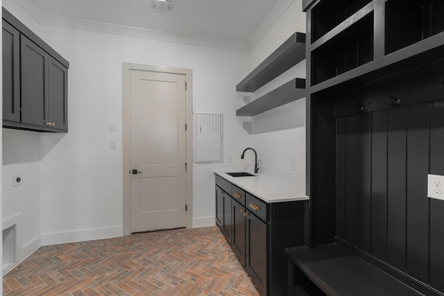 washroom featuring hookup for an electric dryer, visible vents, cabinet space, a sink, and brick floor