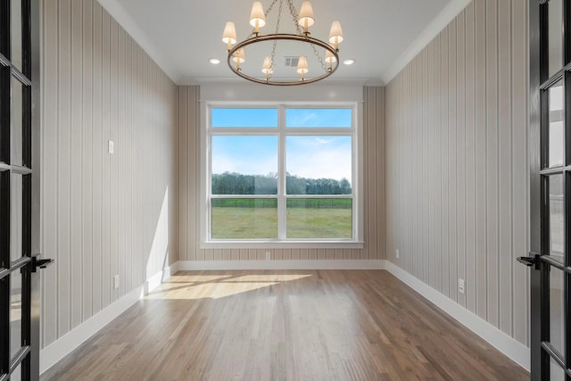 unfurnished room featuring baseboards, ornamental molding, wood finished floors, and a chandelier
