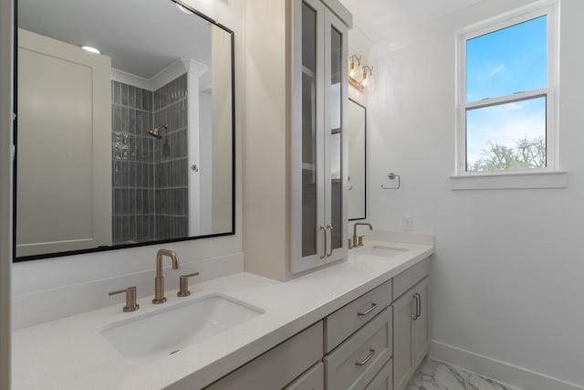 bathroom featuring a sink, tiled shower, double vanity, and marble finish floor