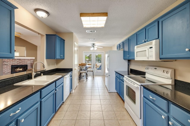 kitchen featuring visible vents, a ceiling fan, a sink, white appliances, and blue cabinets