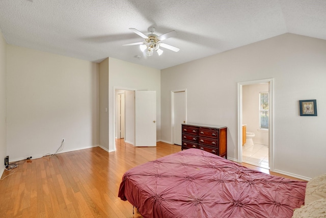 bedroom with a textured ceiling, ensuite bath, lofted ceiling, and light wood-style floors