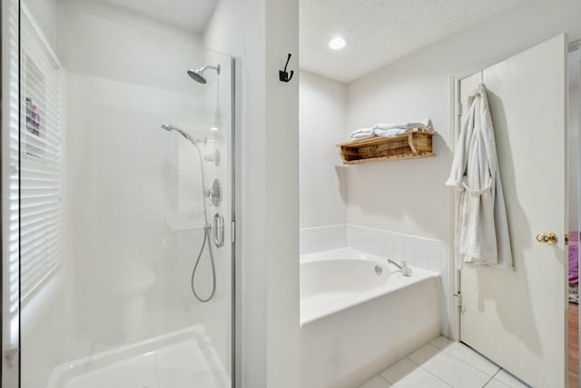 bathroom with a bath, a textured ceiling, tile patterned floors, and a shower stall